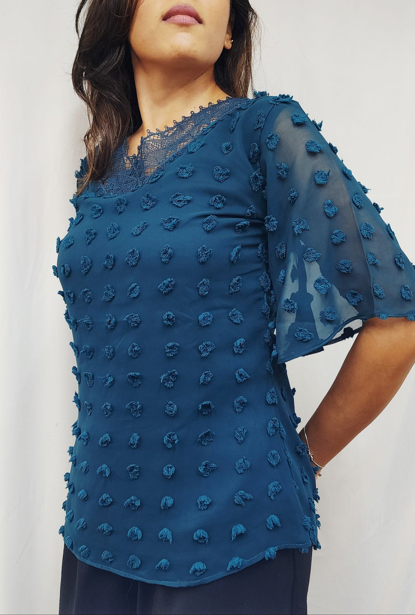 Woman wearing a blue top with a textured pattern on a white background