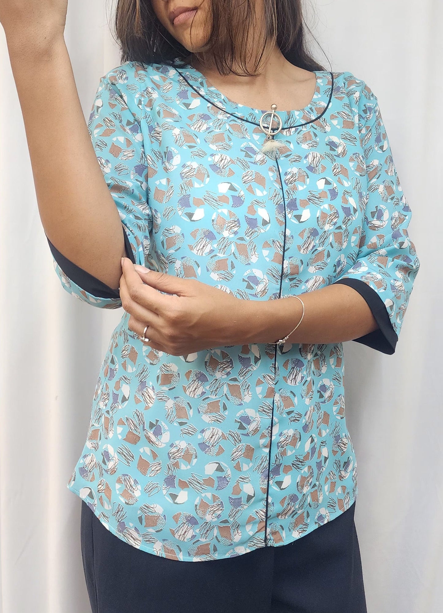 WOMENS ABSTRACT PRINTED TOP IN BLUE WITH ROUND NECK WITH BLACK DETAILING & BROOCH 