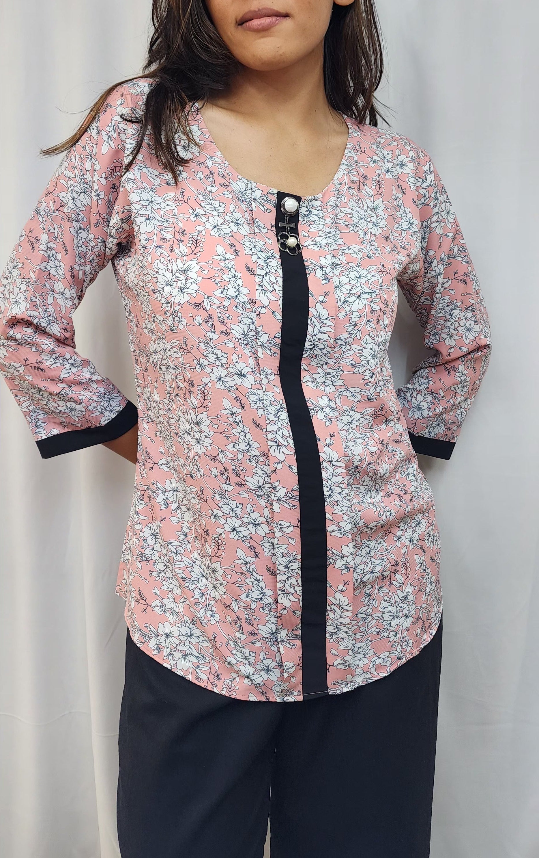 WOMENS FLORAL PRINTED TOP IN PEACK WITH ROUND NECK & BOX PLEAT IN THE FRONT. BLACK BAND DETAILING ON FRONT & SLEEVES. BROOCH ACCENT