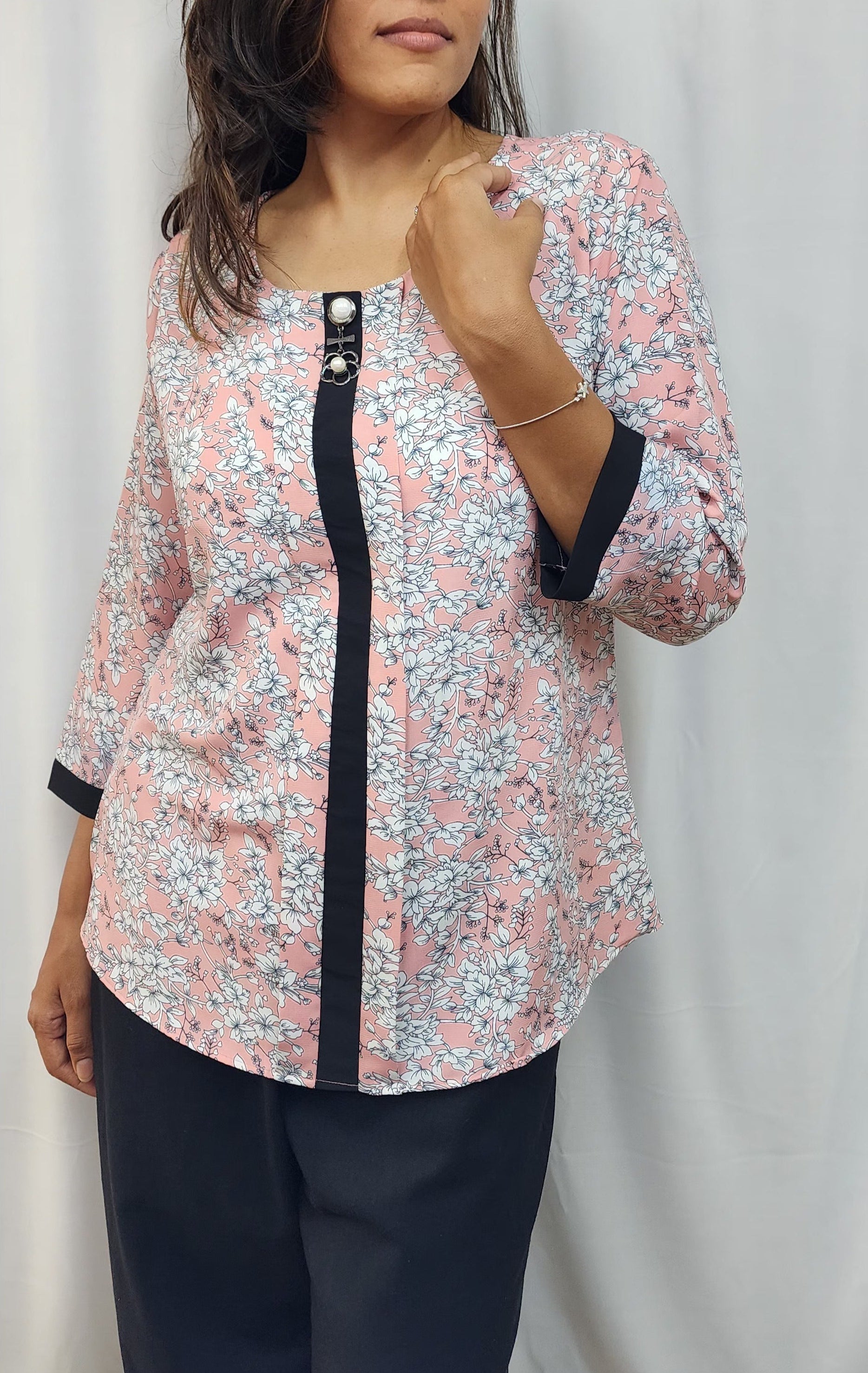 WOMENS FLORAL PRINTED TOP IN PEACK WITH ROUND NECK & BOX PLEAT IN THE FRONT. BLACK BAND DETAILING ON FRONT & SLEEVES. BROOCH ACCENT