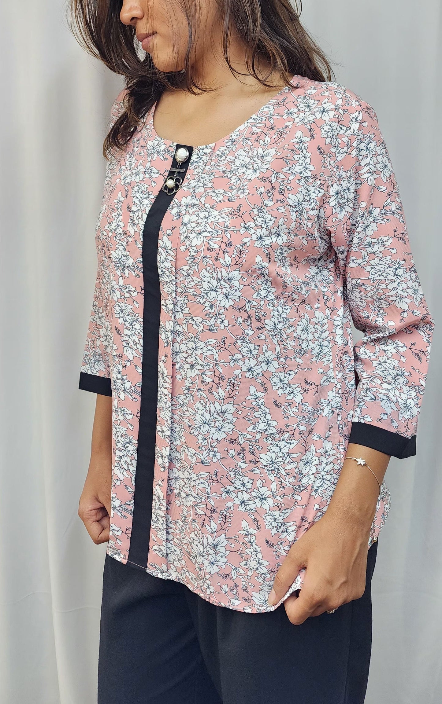 WOMENS FLORAL PRINTED TOP IN PEACK WITH ROUND NECK & BOX PLEAT IN THE FRONT. BLACK BAND DETAILING ON FRONT & SLEEVES. BROOCH ACCENT