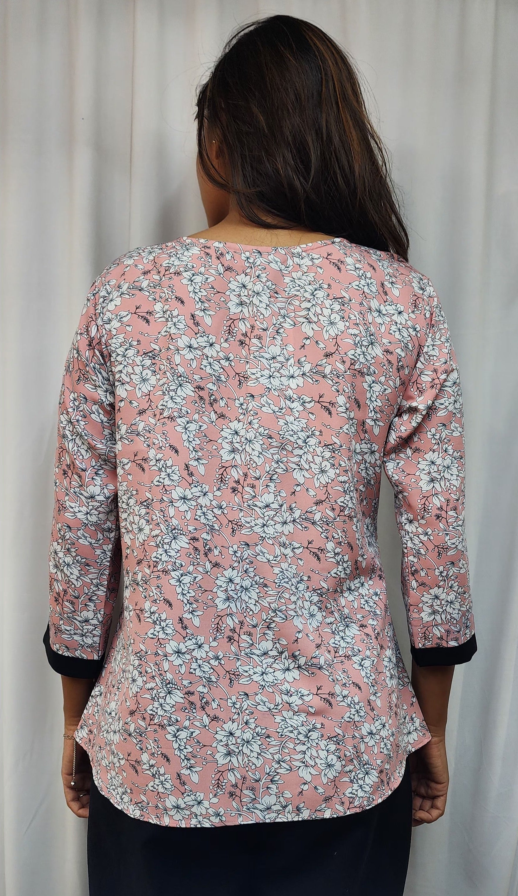 WOMENS FLORAL PRINTED TOP IN PEACK WITH ROUND NECK & BOX PLEAT IN THE FRONT. BLACK BAND DETAILING ON FRONT & SLEEVES. BROOCH ACCENT