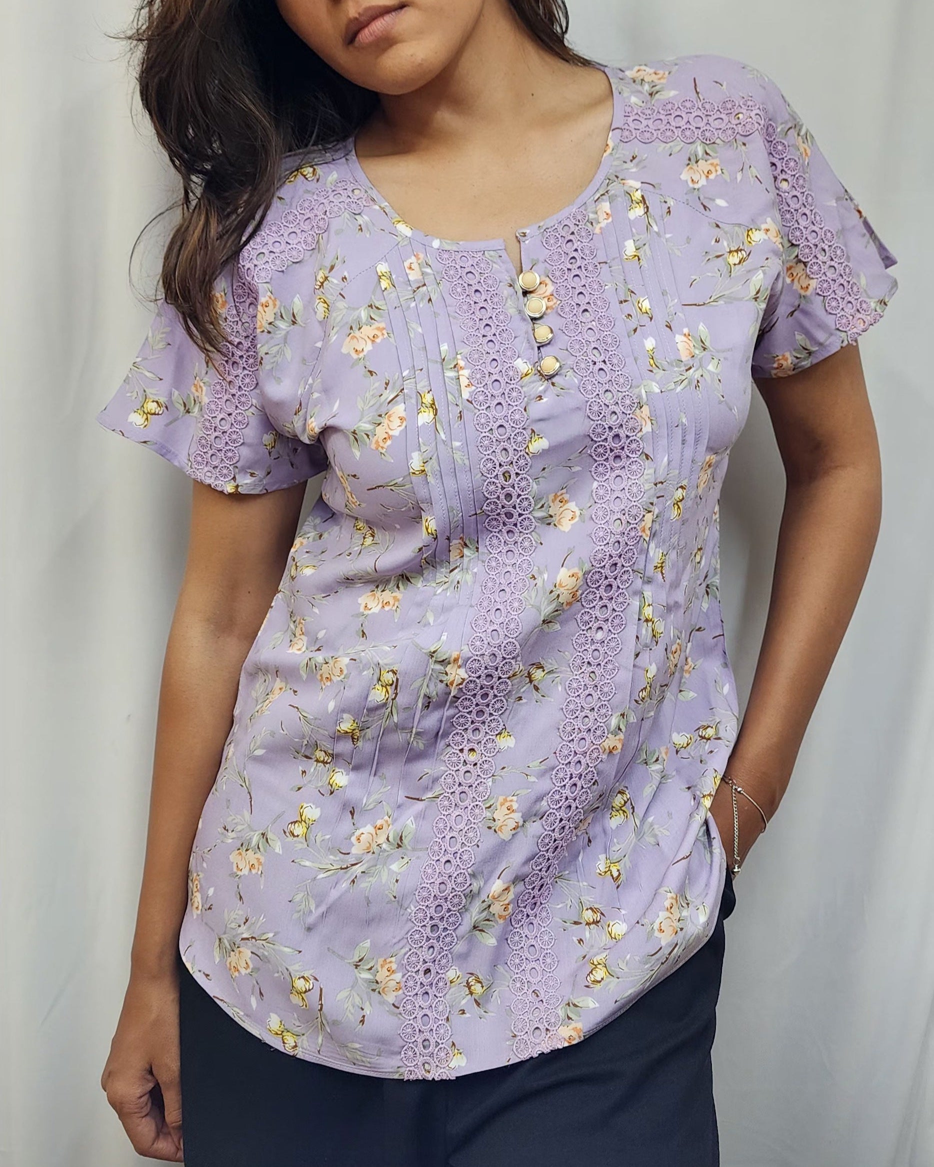 WOMENS FLORAL PRINTED TOP WITH LACE DETAILING. PINTUCKS ON FRONT PANEL, BUTTON ACCENTS ON ROUND NECK, SHORT SLEEVES