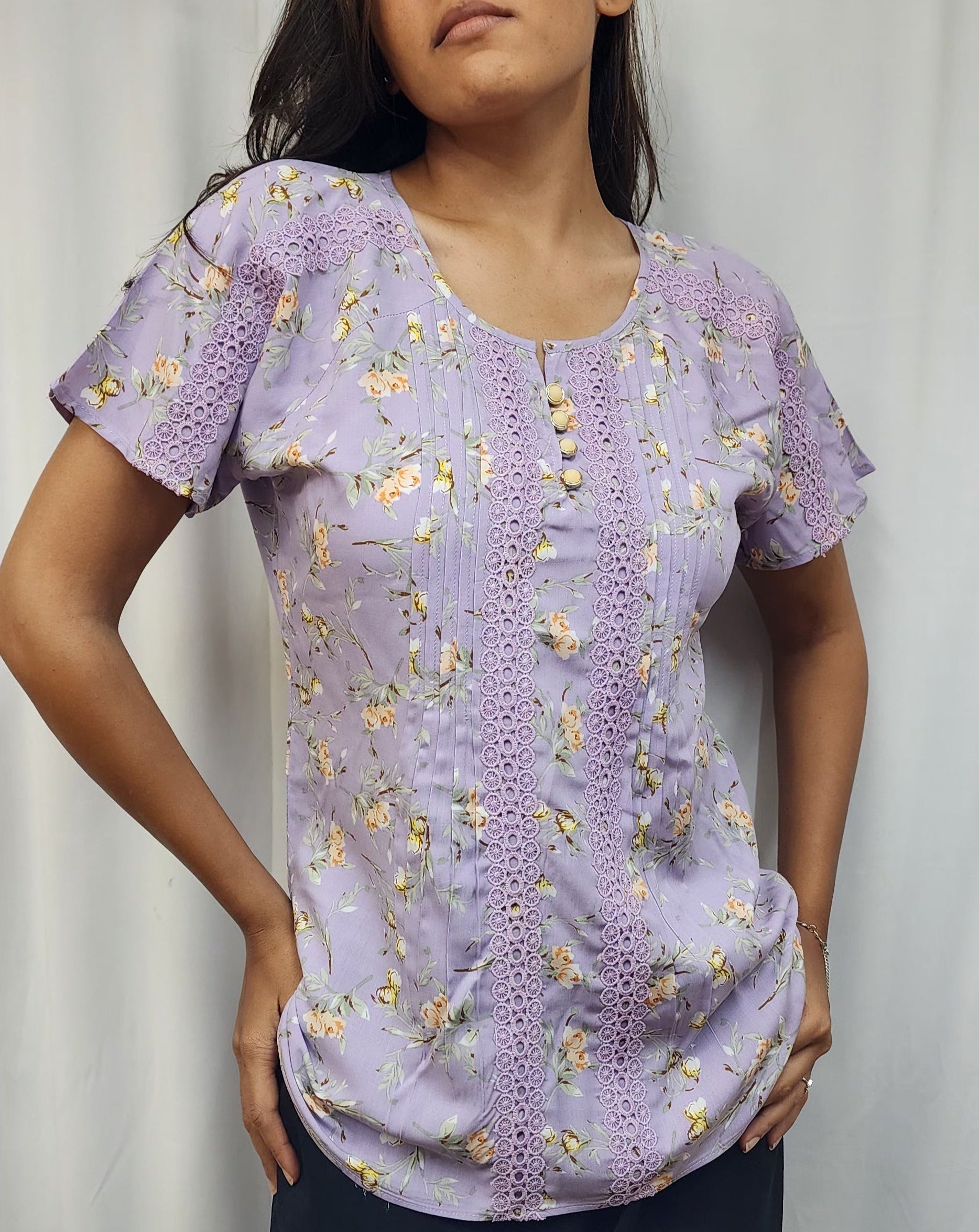 WOMENS FLORAL PRINTED TOP WITH LACE DETAILING. PINTUCKS ON FRONT PANEL, BUTTON ACCENTS ON ROUND NECK, SHORT SLEEVES