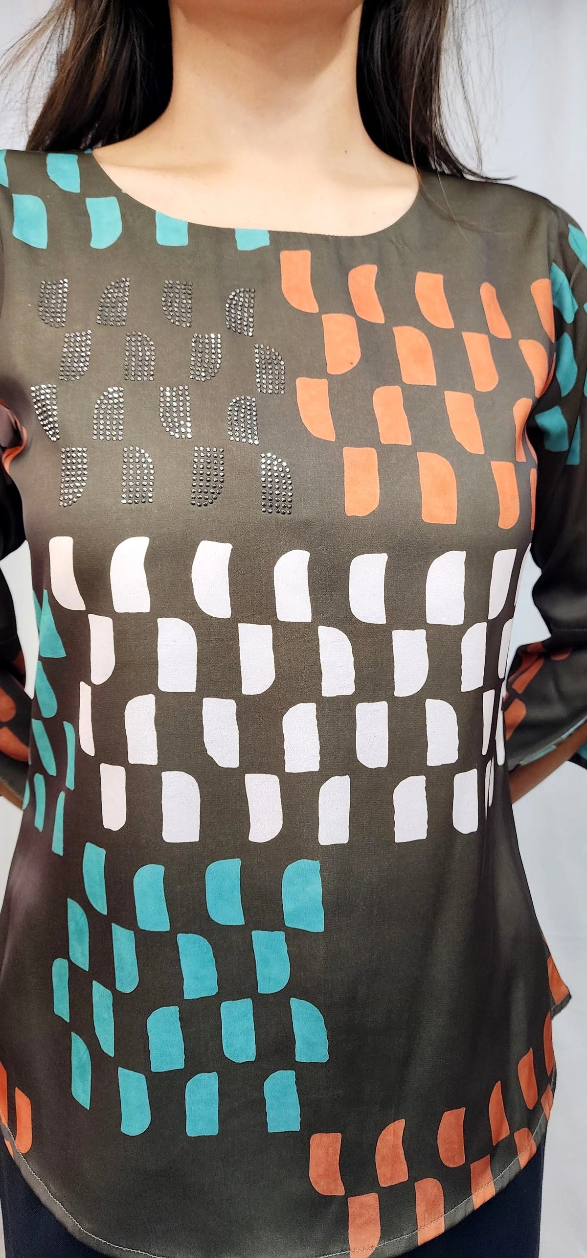 A close-up of a woman wearing a sheer black mesh top with a geometric pattern of white, orange, and teal shapes.